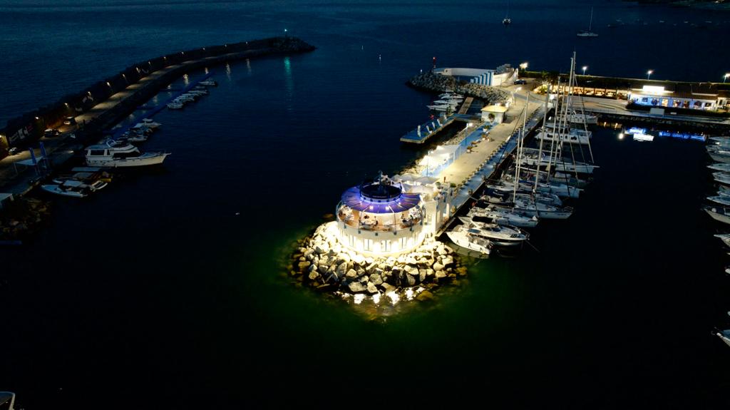 Vista dall'alto del Marina Yacht Club di sera, con vista sul porto e sul ristorante