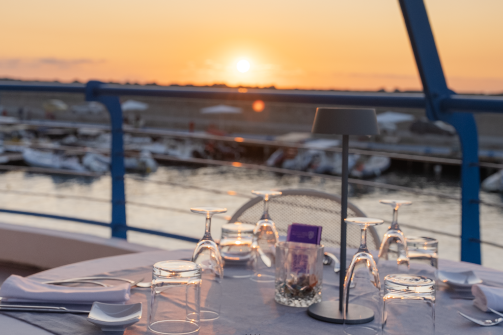 Tavolo apparecchiato al Marina Yacht Club con vista sul porto al tramonto