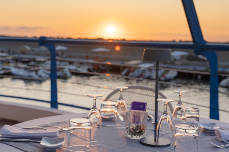 Tavolo apparecchiato al Marina Yacht Club con vista sul porto al tramonto